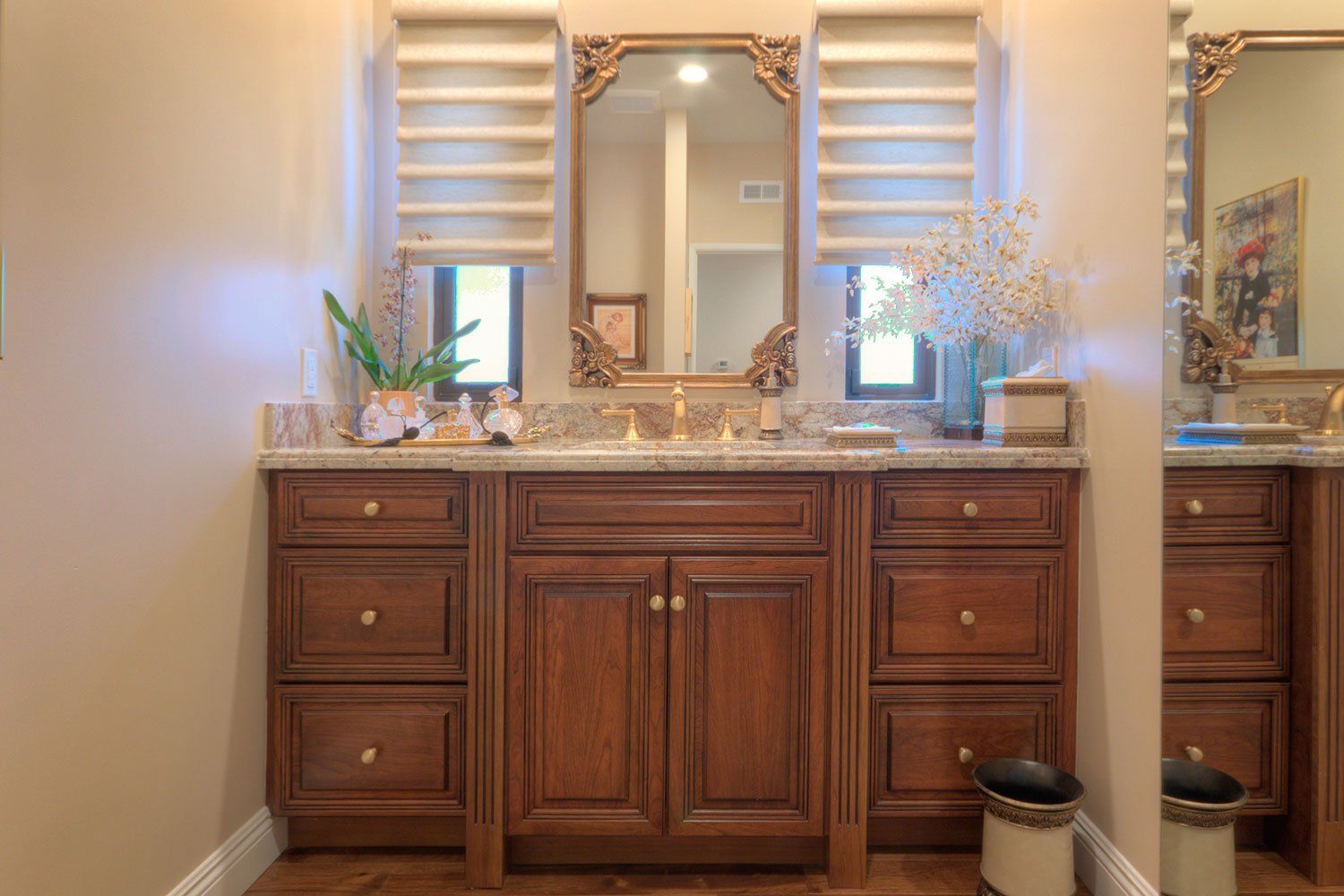 Wooden bathroom vanity with marble countertop, mirror, wall sconces, and decorative plants.