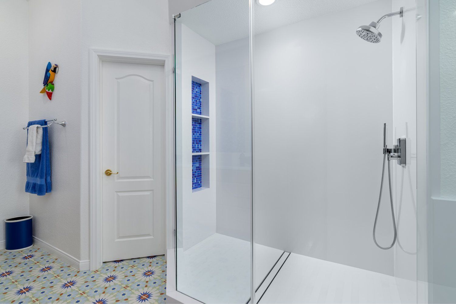 Bright bathroom with glass shower, white door, and colorful towel accents