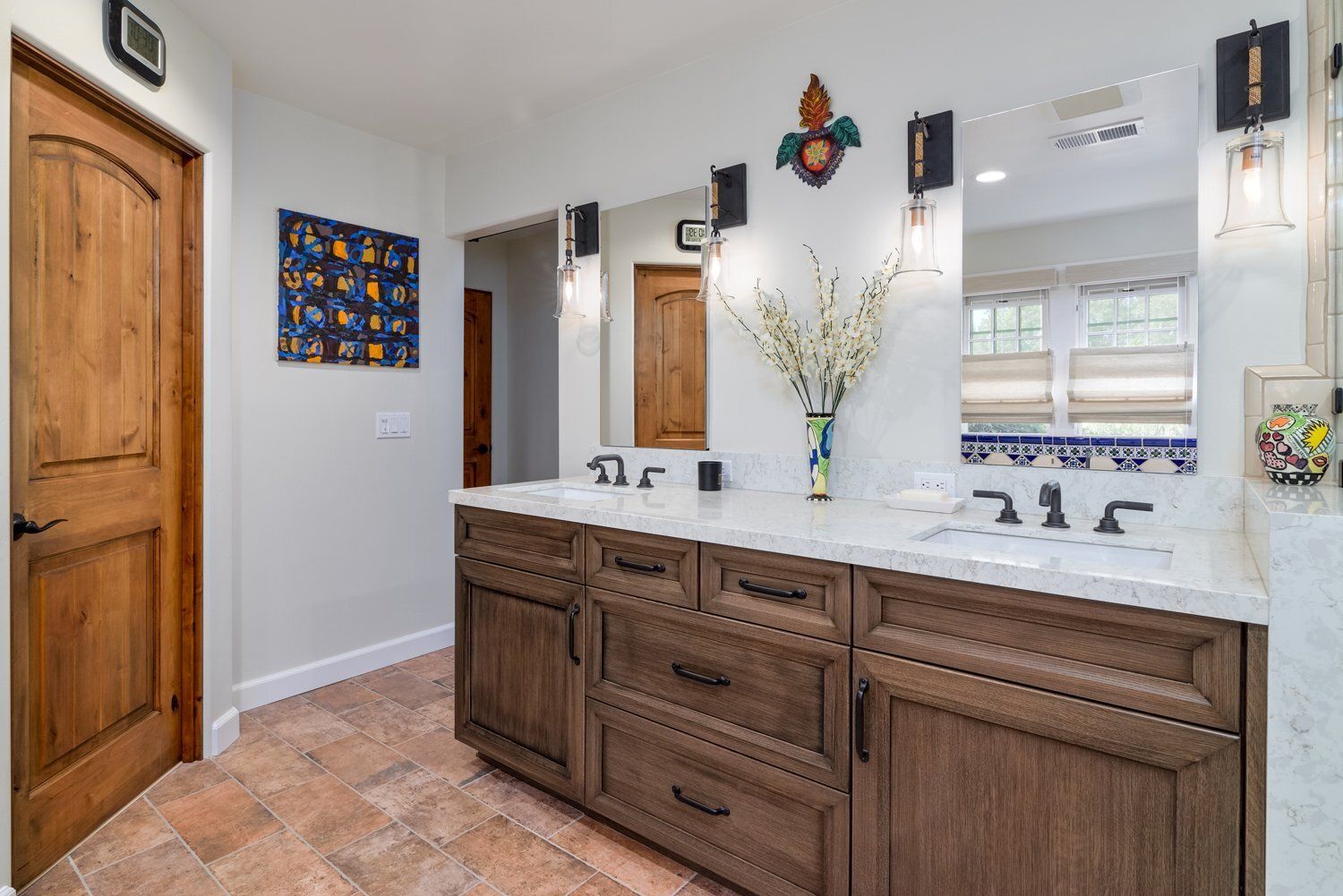 Bright bathroom with double vanity, marble countertop, wood cabinets, and wall mirror.