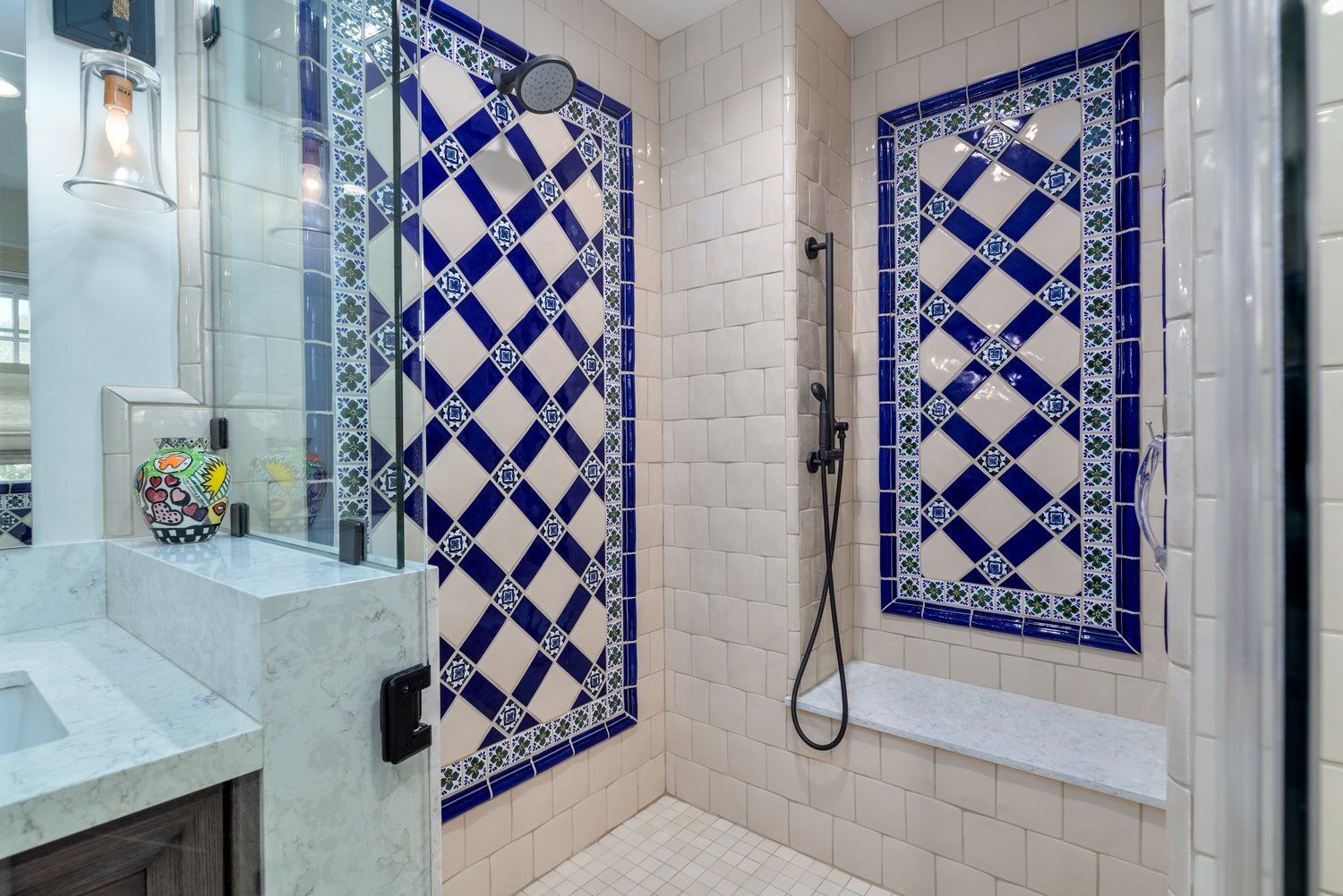 Bathroom with white tile walls, blue diamond mosaic accents, vanity sink, and shower area