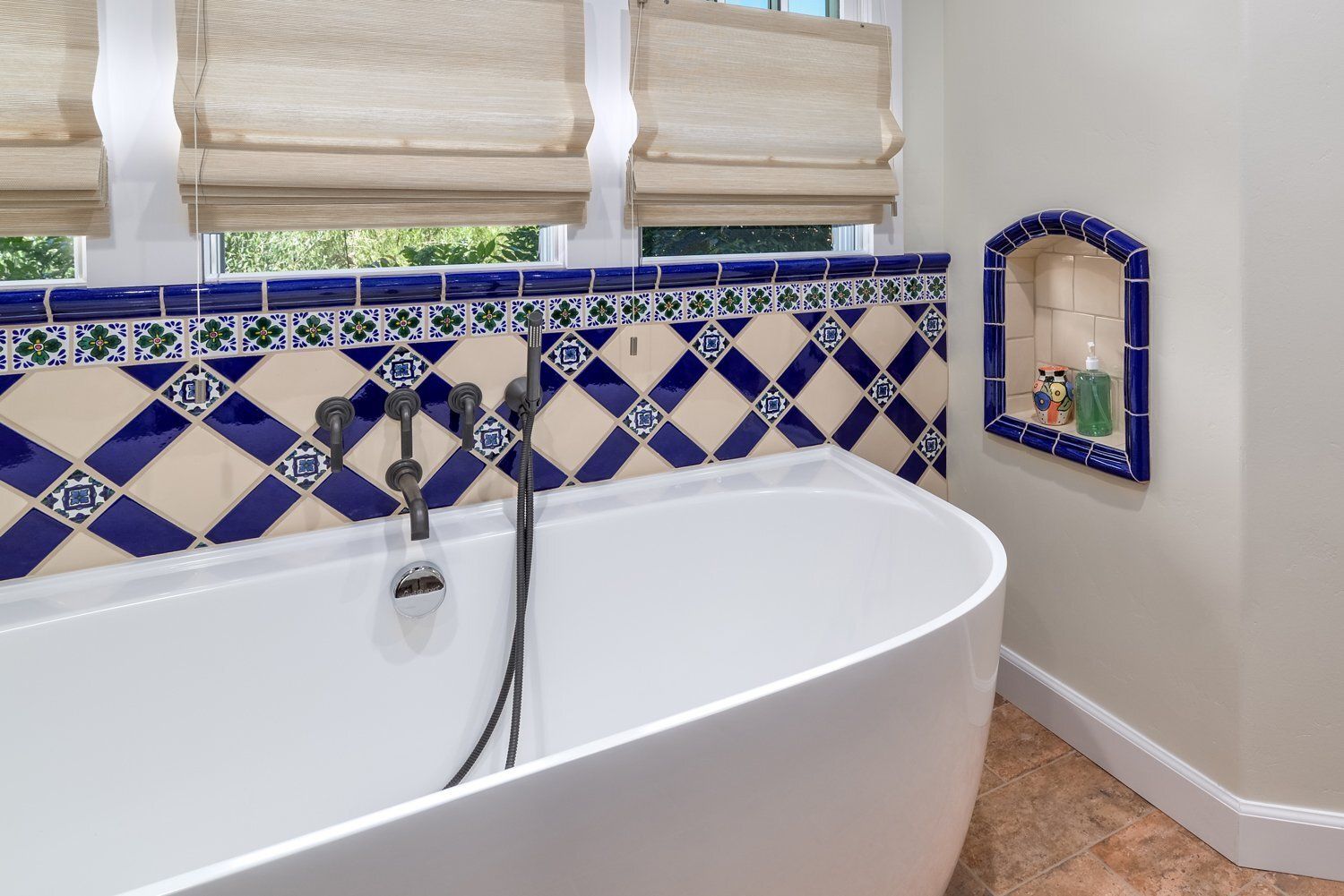 Bathtub with blue-and-white tile surround and a small tiled wall niche in a bathroom
