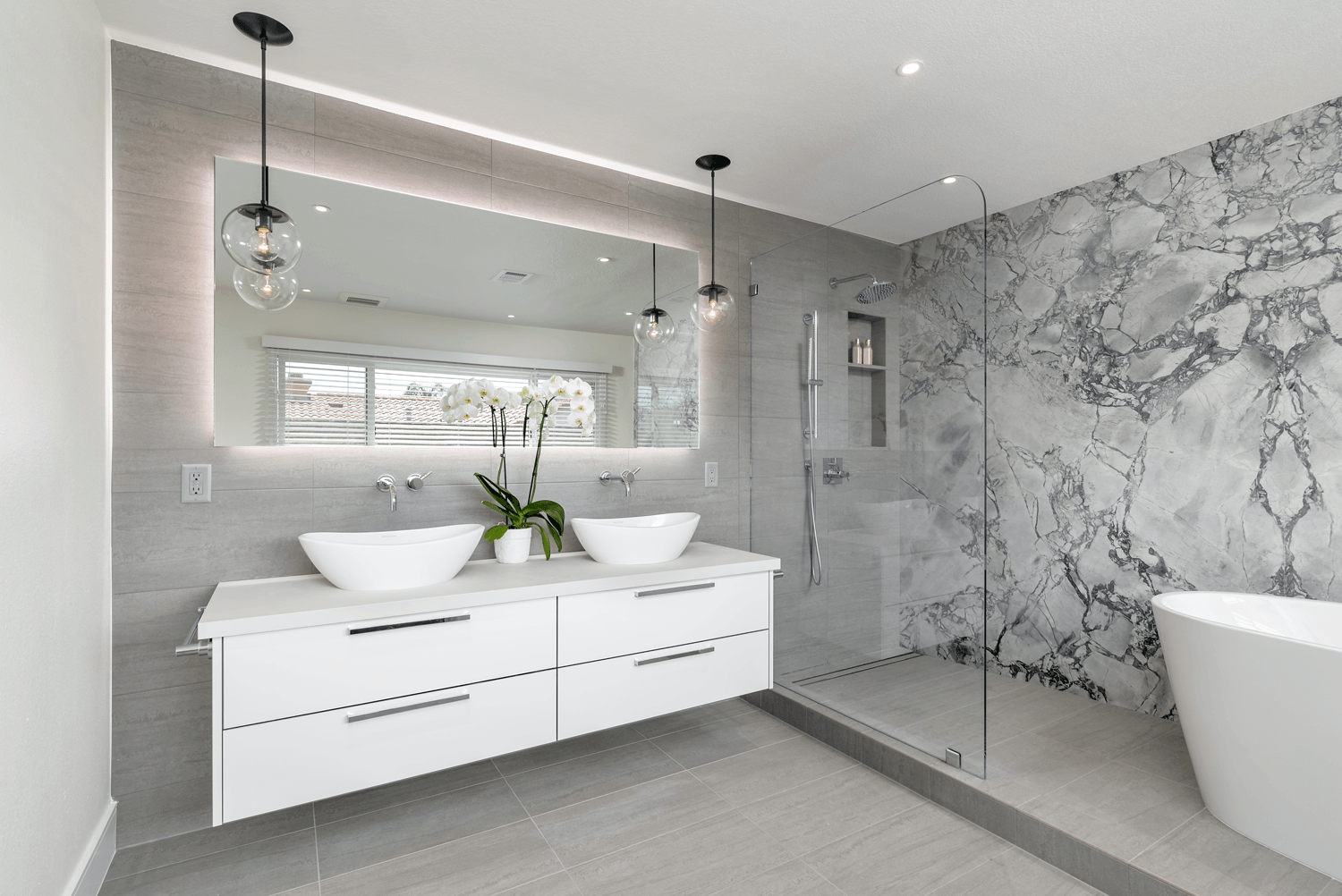 Bright modern bathroom with double sinks, large mirror, marble shower, and freestanding tub