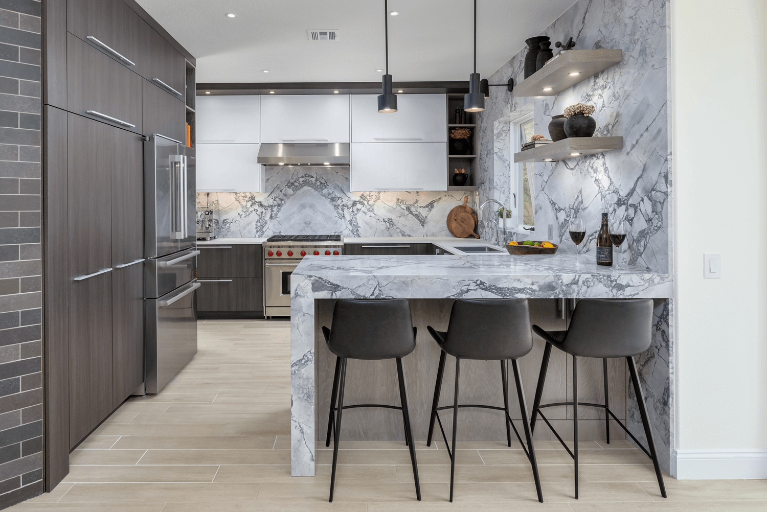 Modern kitchen with marble island, gray bar stools, stainless appliances, and patterned backsplash