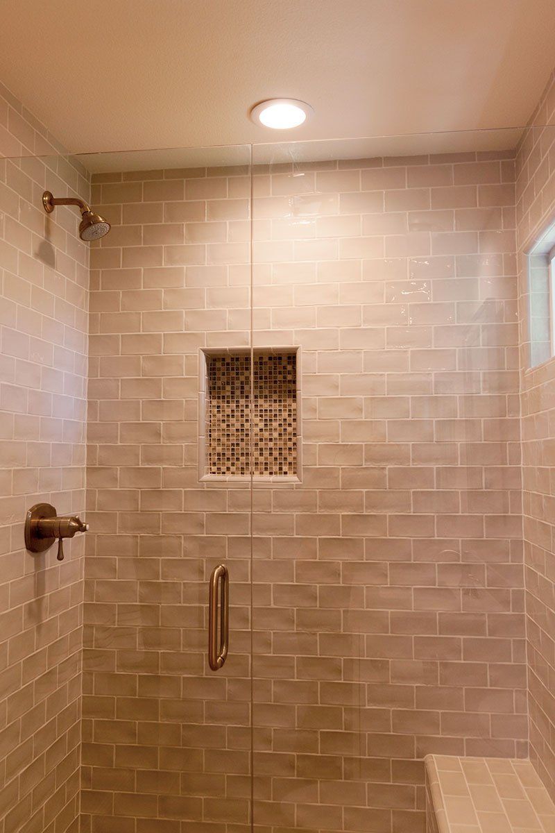 Glass shower with beige subway tile, built-in niche, and a ceiling light.