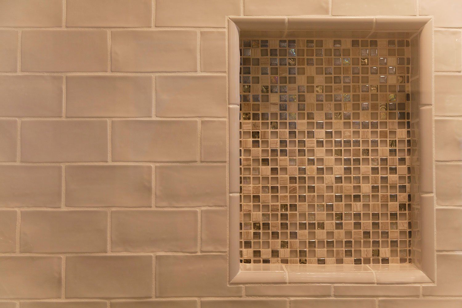 Beige tiled wall with a recessed square mosaic-tile niche or shelf