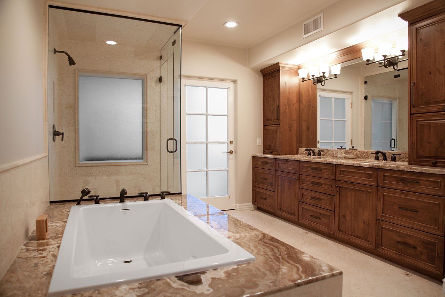 Luxurious bathroom with freestanding tub, glass shower, and wooden vanity with double sinks