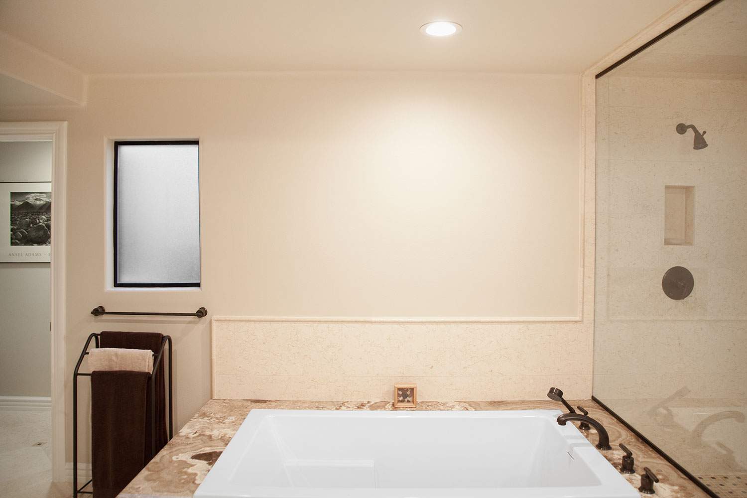 Modern bathroom with a soaking tub, beige walls, and glass shower enclosure