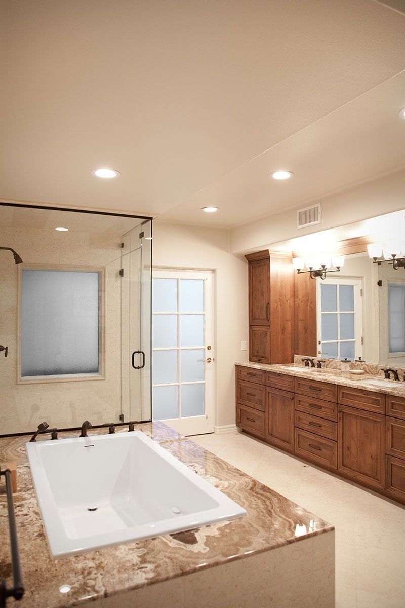 Modern bathroom with freestanding tub, double vanity, large mirror, and beige tile finishes
