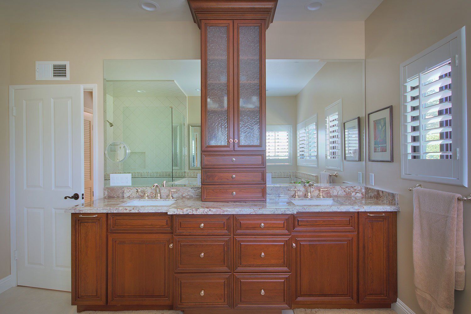 Bathroom vanity with wood cabinets, granite countertop, central mirror, and white shutters on the windows