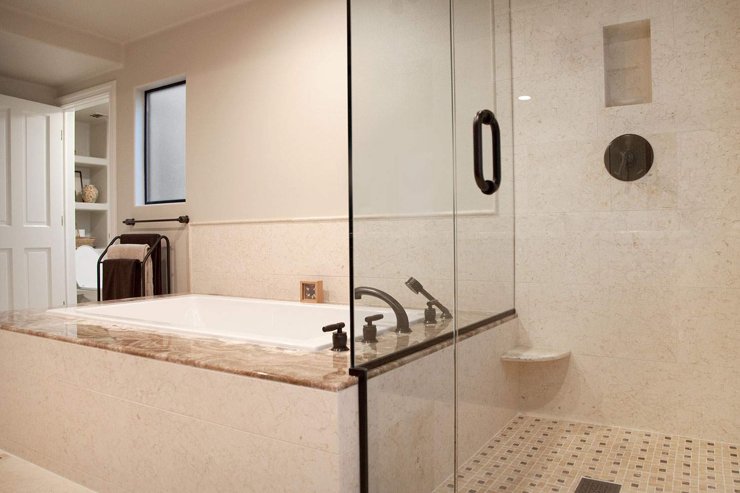 Modern bathroom with glass shower, marble vanity, and neutral tile walls