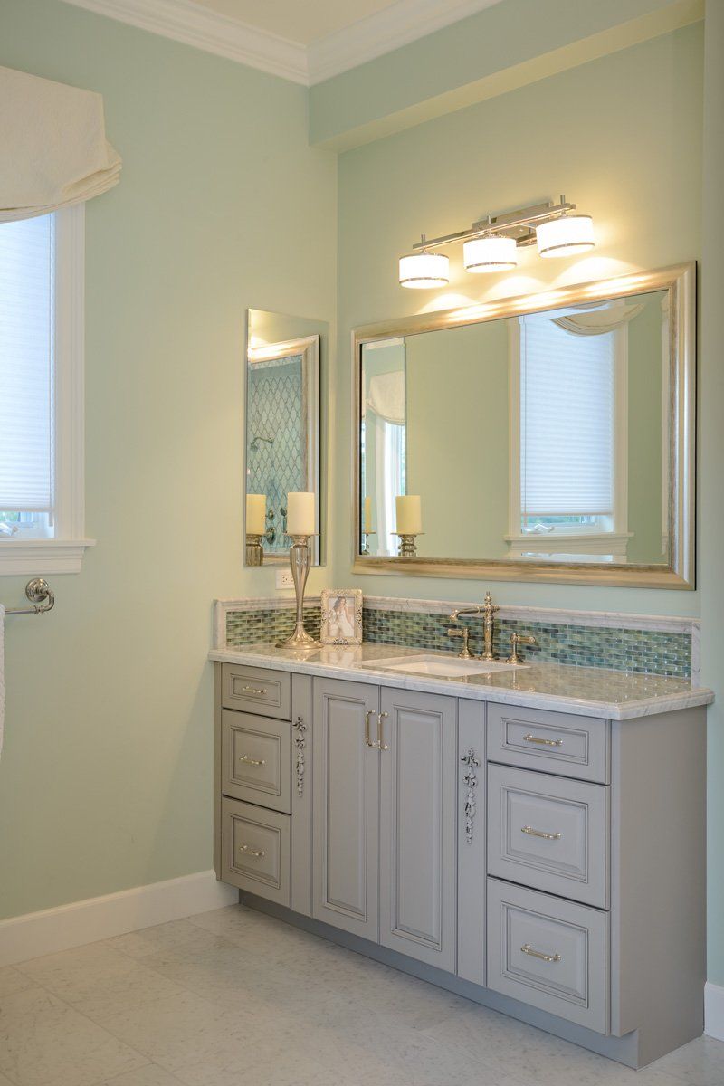 Bathroom vanity with double sinks, large mirror, and wall lights in a pale green room
