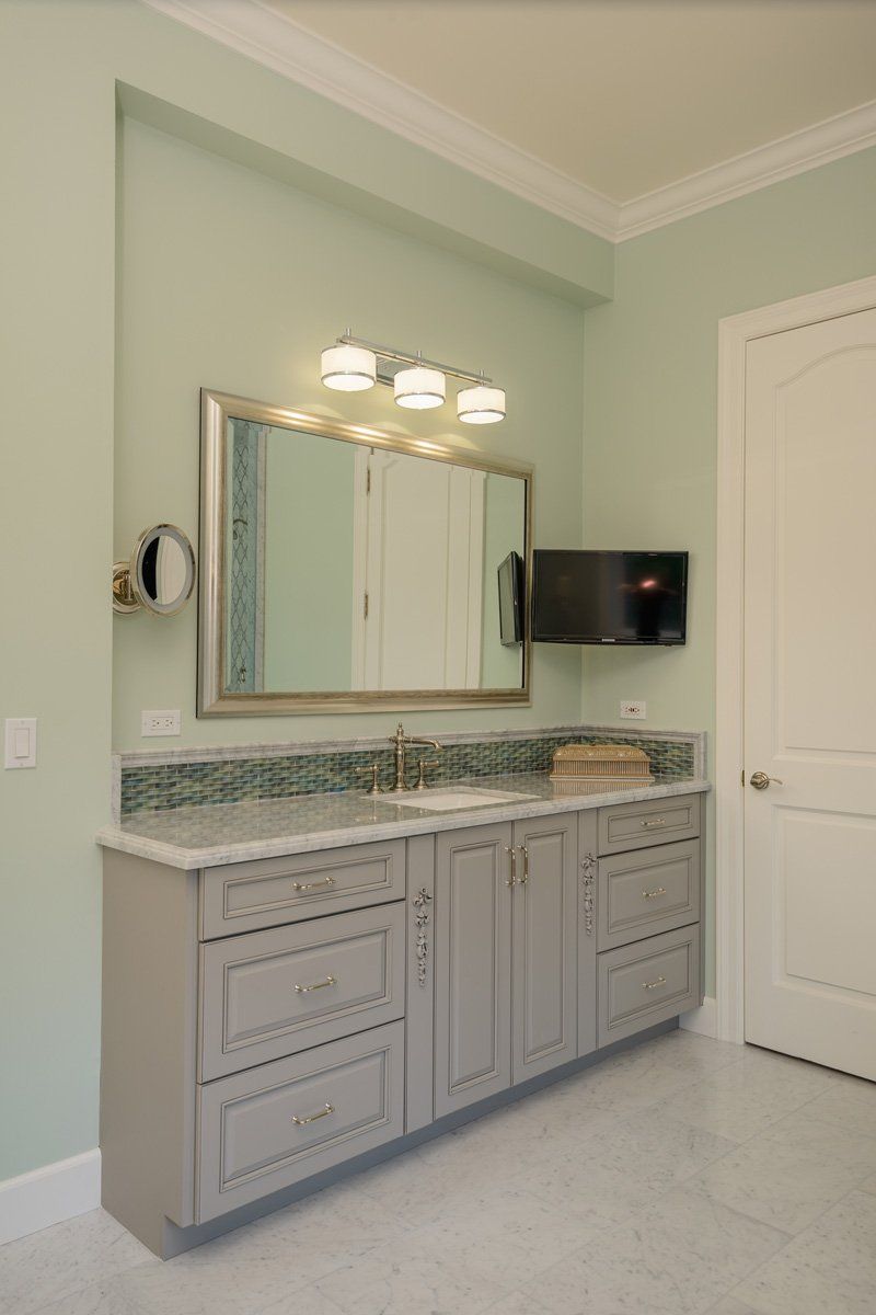 Modern bathroom vanity with double sinks, large mirror, wall lights, and pale green walls.
