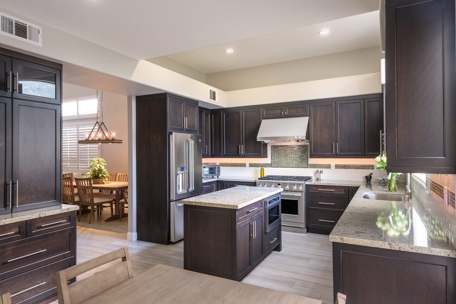 Modern kitchen with dark cabinets, stainless appliances, island, and granite countertops