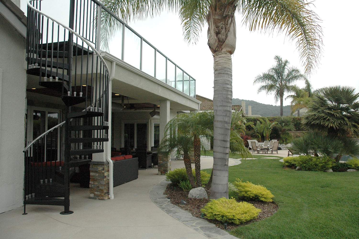 Apartment courtyard with spiral stairs, palm trees, and manicured lawn
