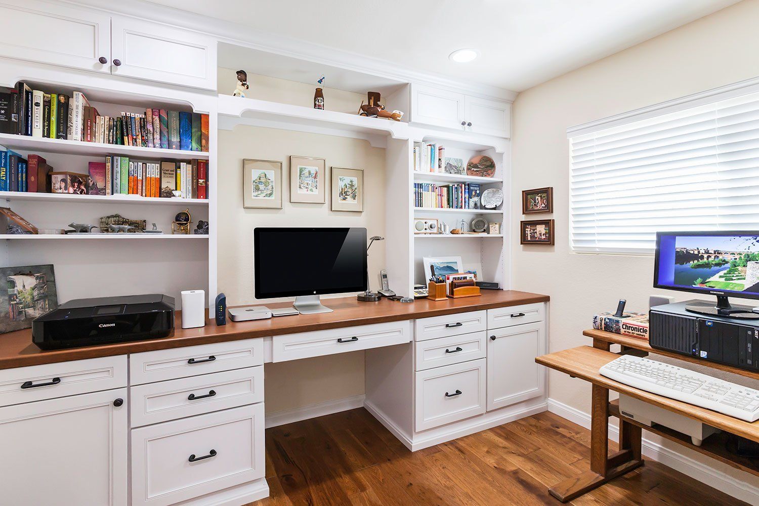 Bright home office with white built-ins, wood desk, computer monitor, and bookshelves.