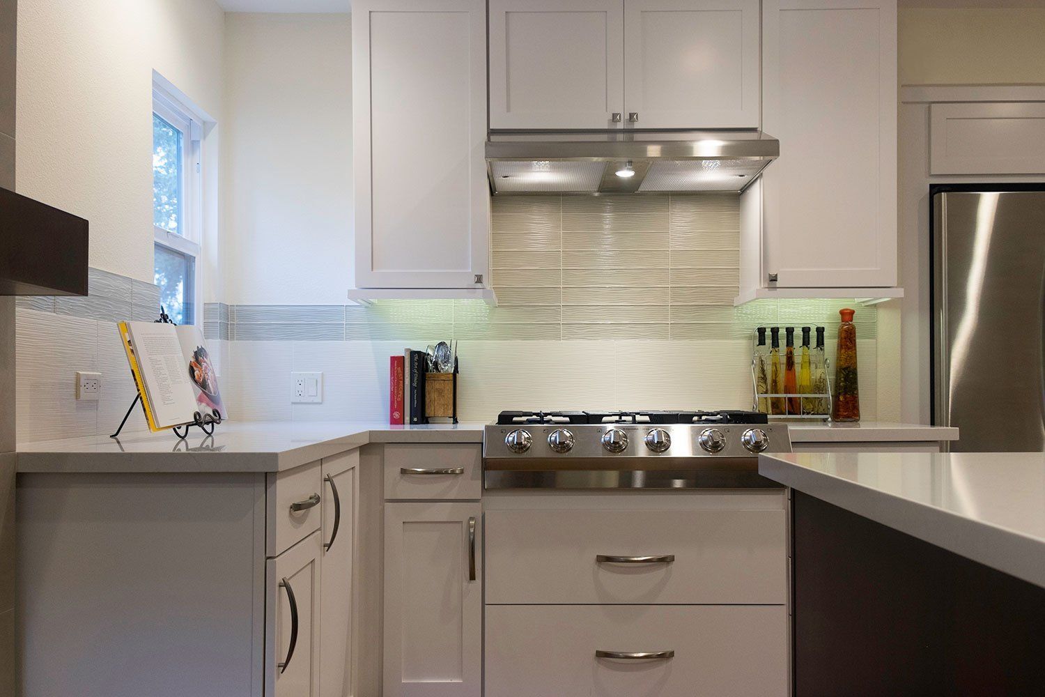 Modern kitchen with white cabinets, stainless steel appliances, and a countertop island