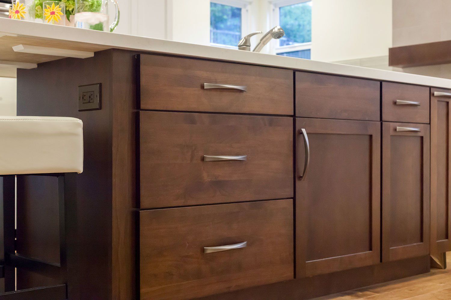 Dark wood kitchen cabinets beneath a beige countertop near a window