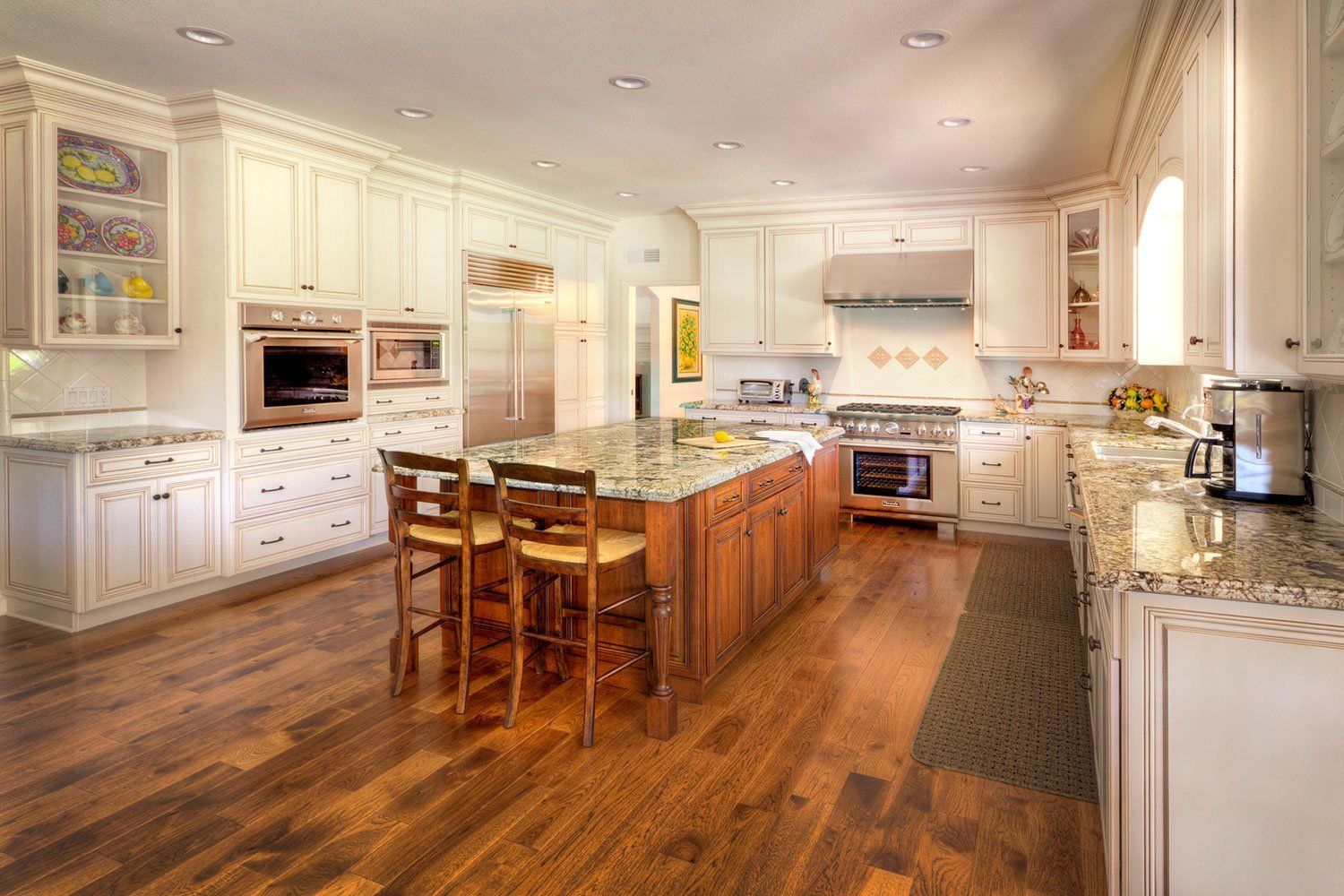 Bright, spacious kitchen with white cabinets, a large wooden island, and hardwood floors