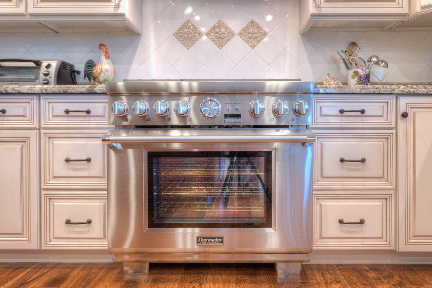 Modern kitchen with stainless steel oven, cream cabinets, and marble countertops