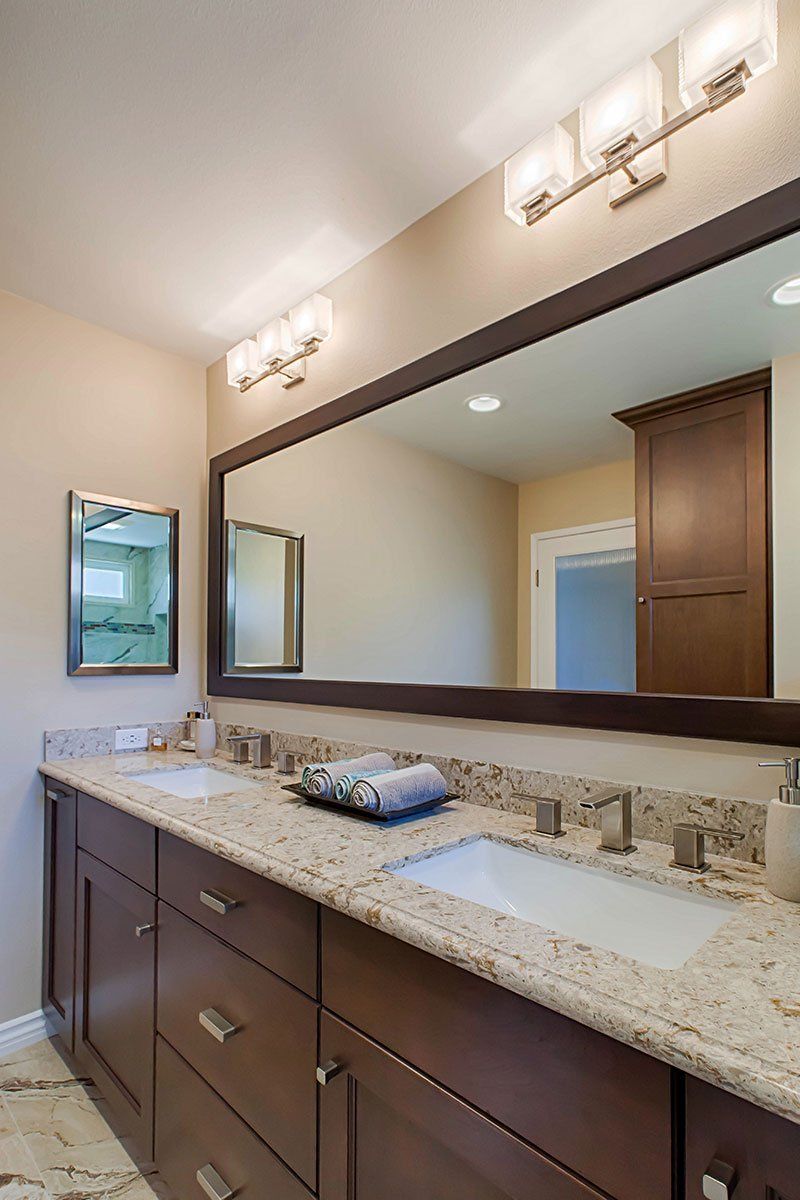 Modern bathroom vanity with double sinks, large mirror, dark wood cabinets, and wall sconces