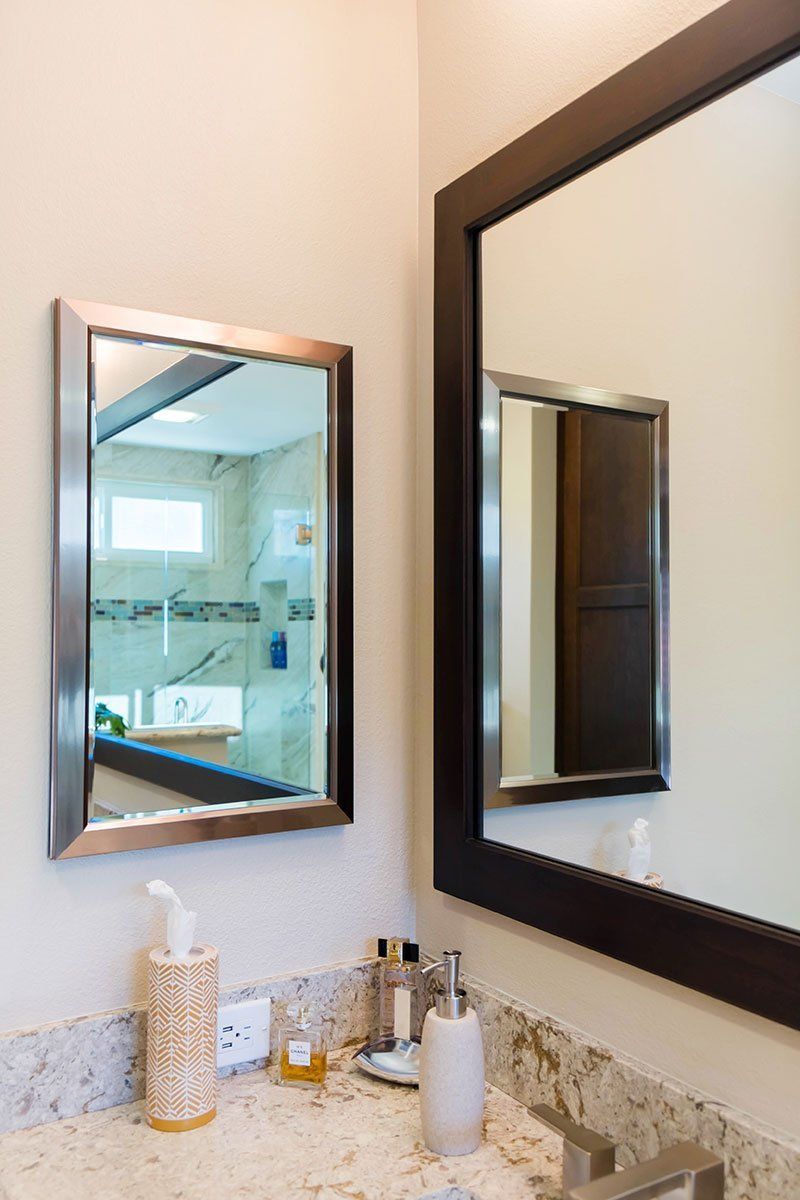 Bathroom vanity with large mirror, wall mirror, sink, soap dispenser, and tiled backsplash