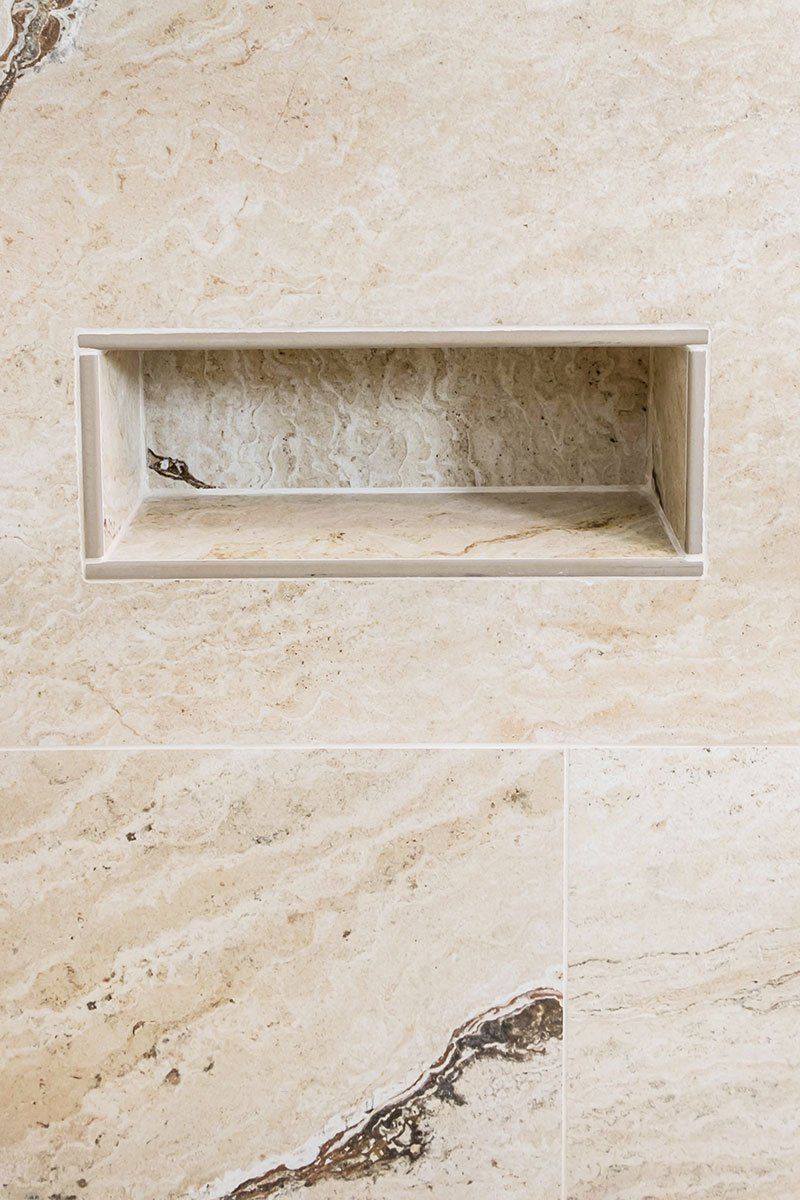 Beige marble wall with a recessed rectangular niche and a small dark vein near the bottom