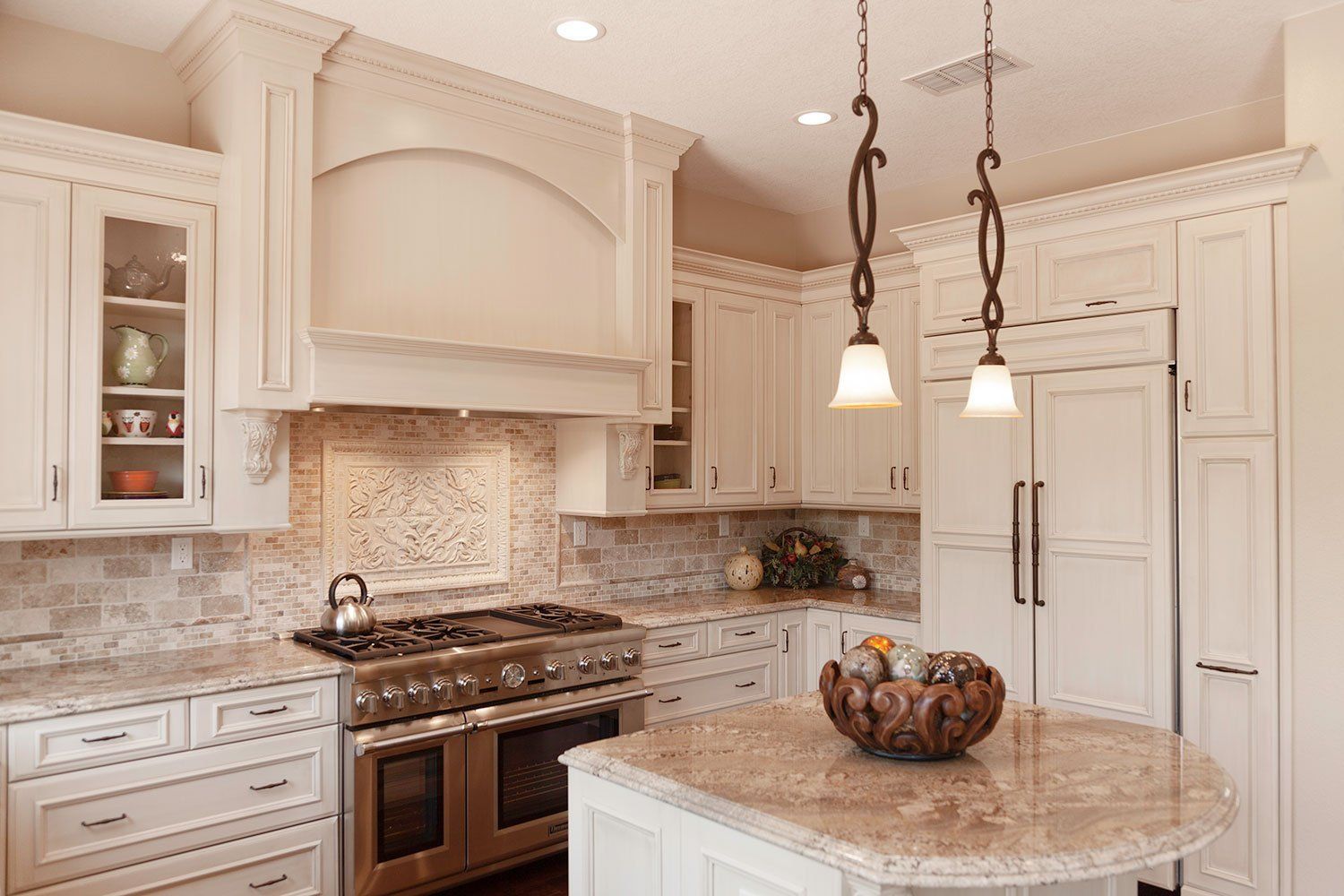 Bright beige kitchen with white cabinets, granite island, stainless stove, and pendant lights.