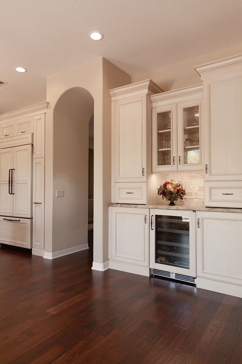 Bright kitchen with white cabinets, arched doorway, and dark hardwood floors