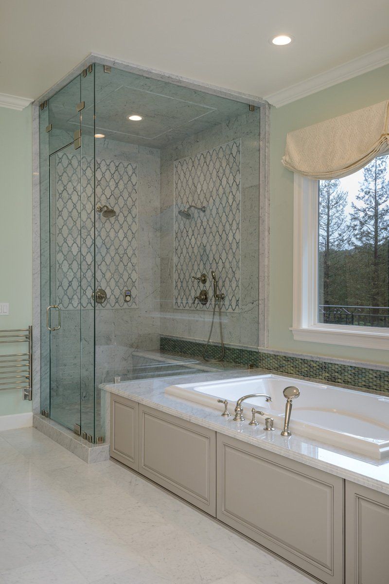Elegant bathroom with glass shower, soaking tub, and large window with beige valance