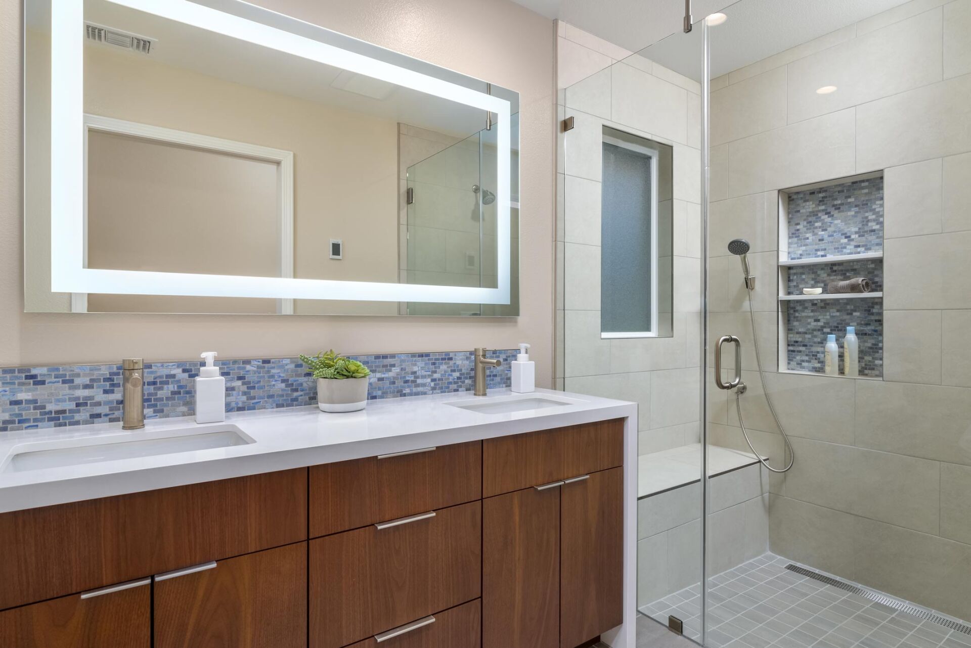Modern bathroom with double vanity, large mirror, and tiled walk-in shower