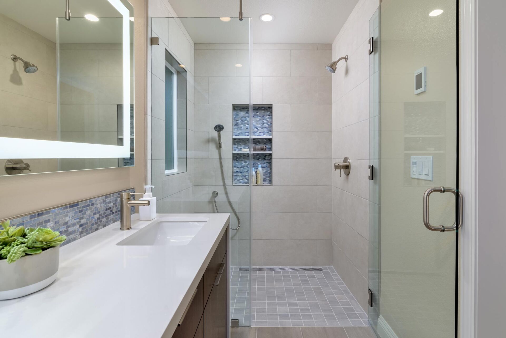 Bright modern bathroom with glass shower, white sink, and tiled walls