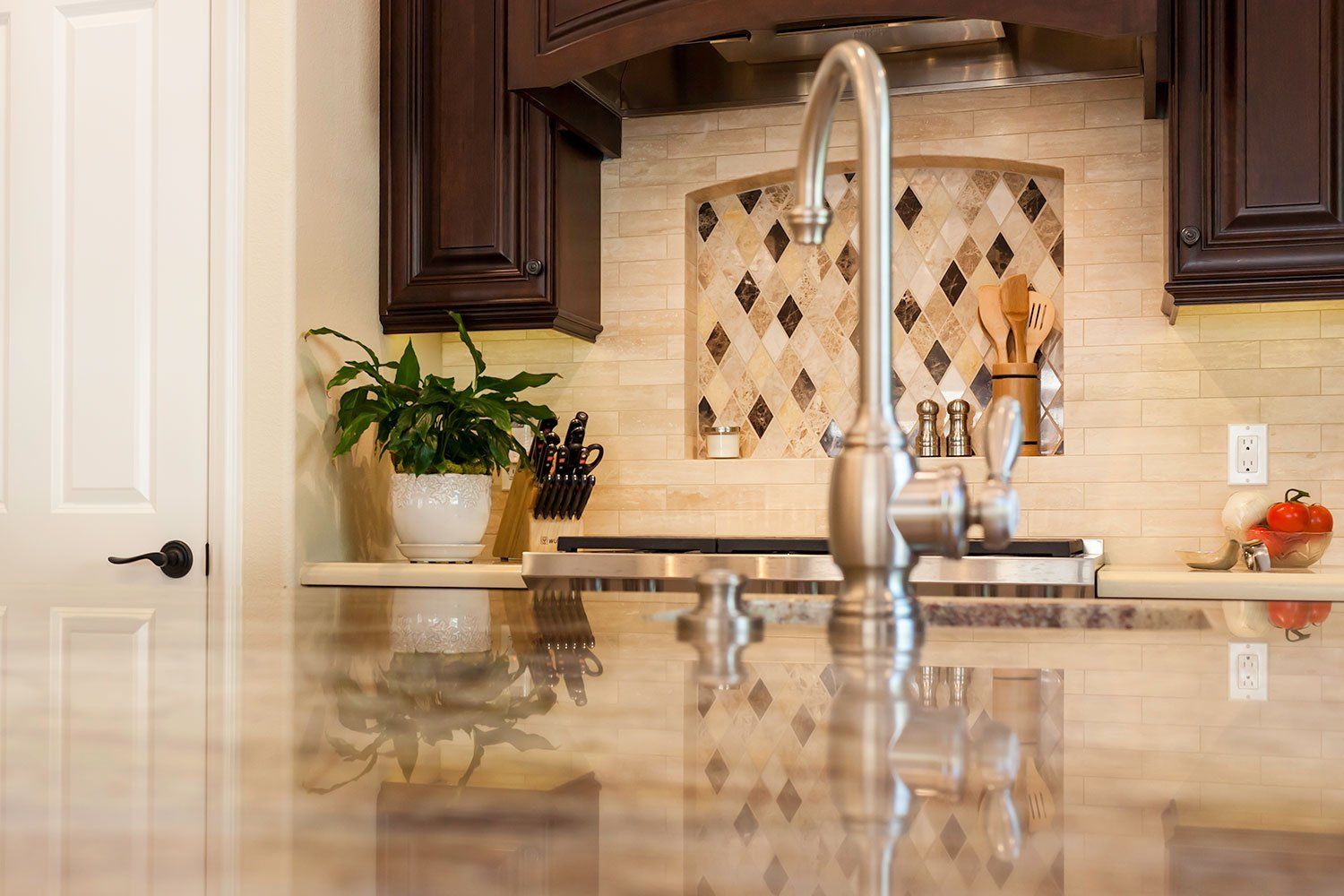 Modern kitchen with granite island, stainless faucet, dark cabinets, and decorative tile backsplash
