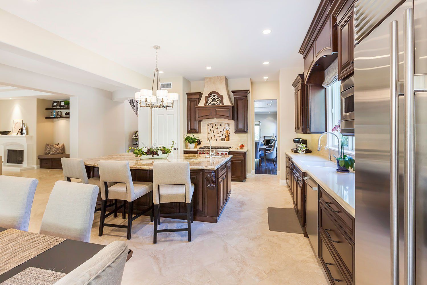 Bright, modern kitchen and dining area with white chairs, wood cabinetry, and a central island
