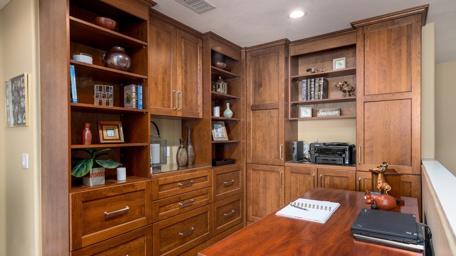 Built-in wooden home office with shelves, cabinets, and a desk by a window