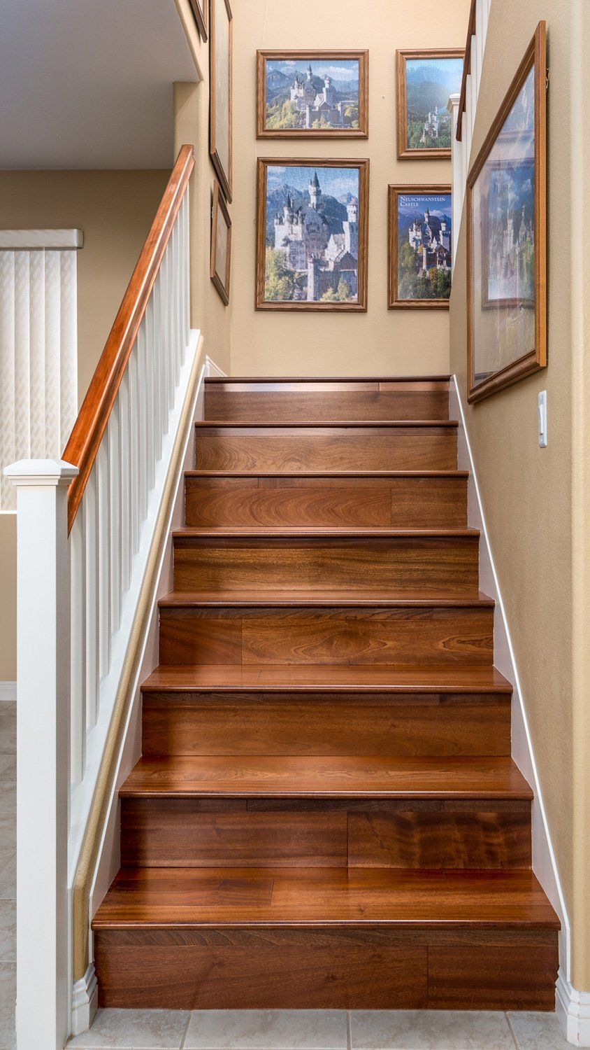 Indoor staircase with wooden steps and framed pictures on the wall at the top landing