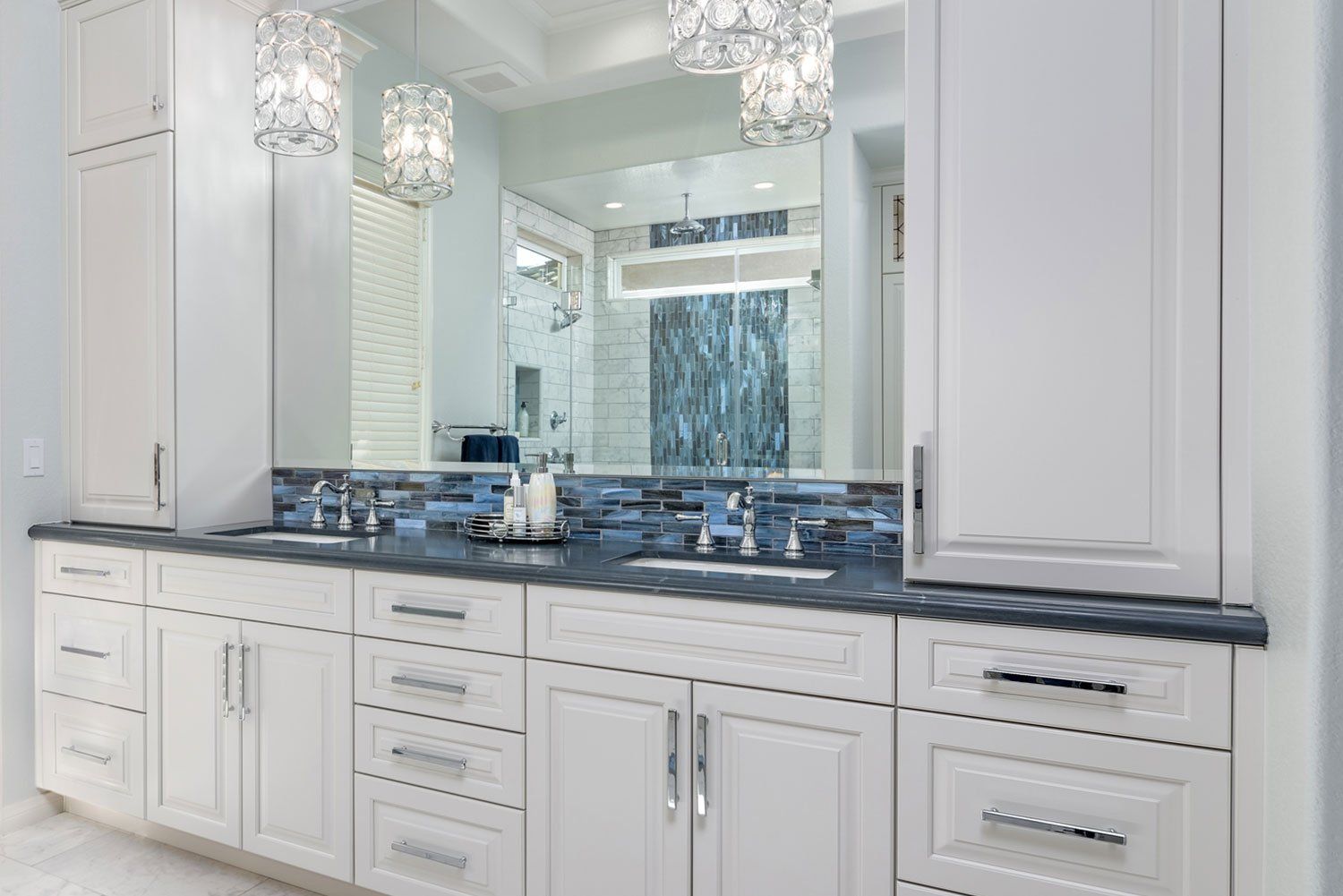 Elegant white bathroom vanity with dark countertop, double sinks, and large mirror wall.