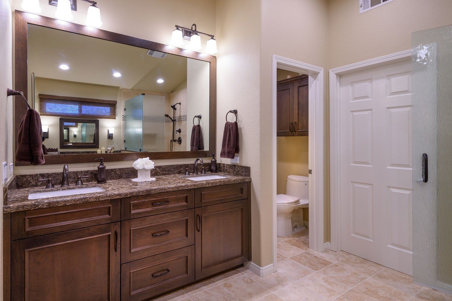 Elegant bathroom with double vanity, large mirror, and glass shower area in neutral tones