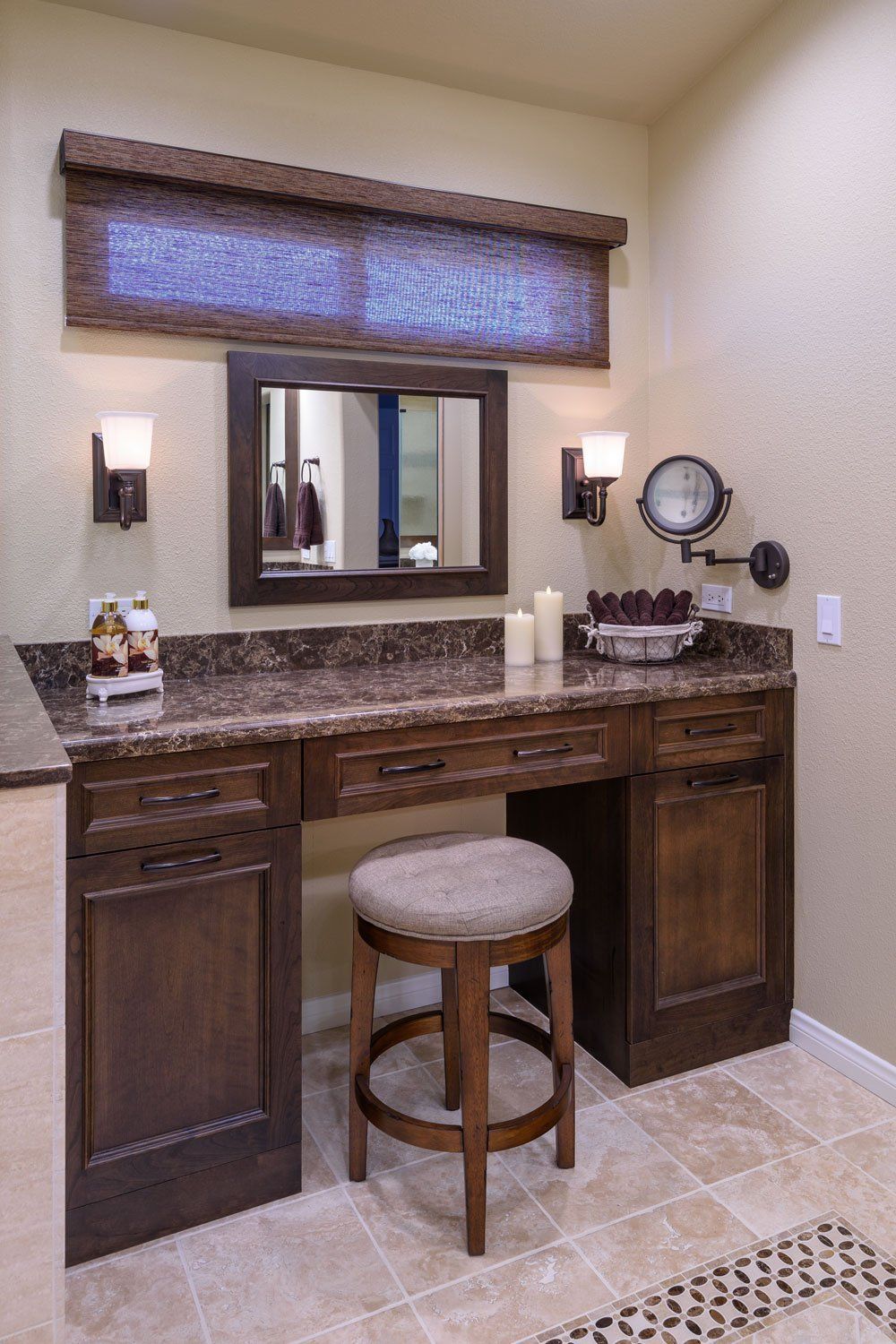 Compact bathroom vanity with dark wood cabinets, granite countertop, mirror, stool, and woven window shade