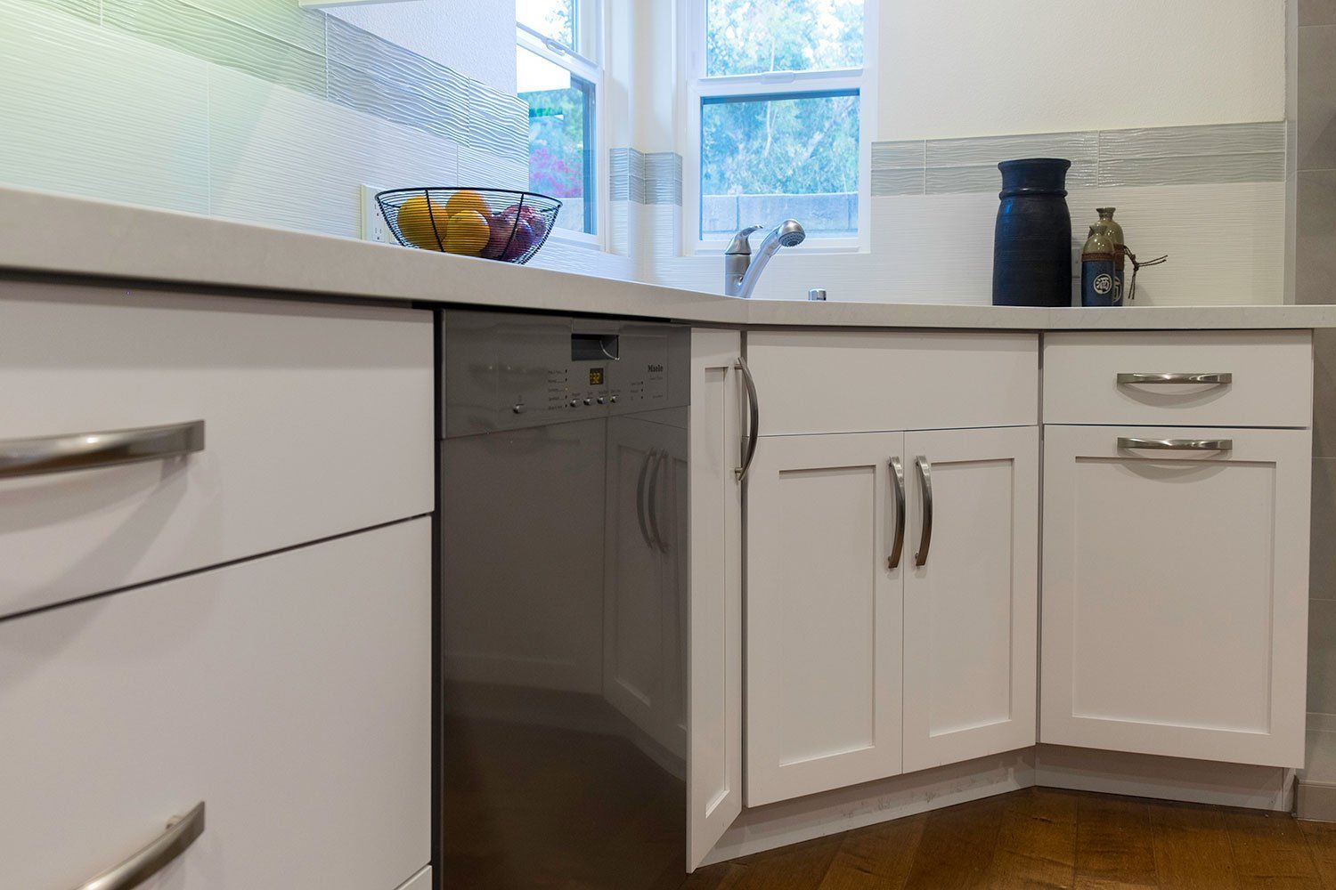 White kitchen with cabinets, sink, dishwasher, and fruit bowl by a window