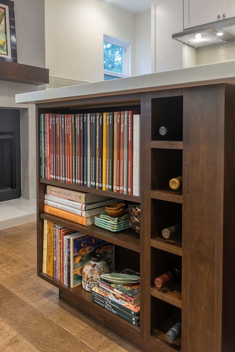Wooden kitchen island with shelves holding vinyl records and baskets in a bright modern home