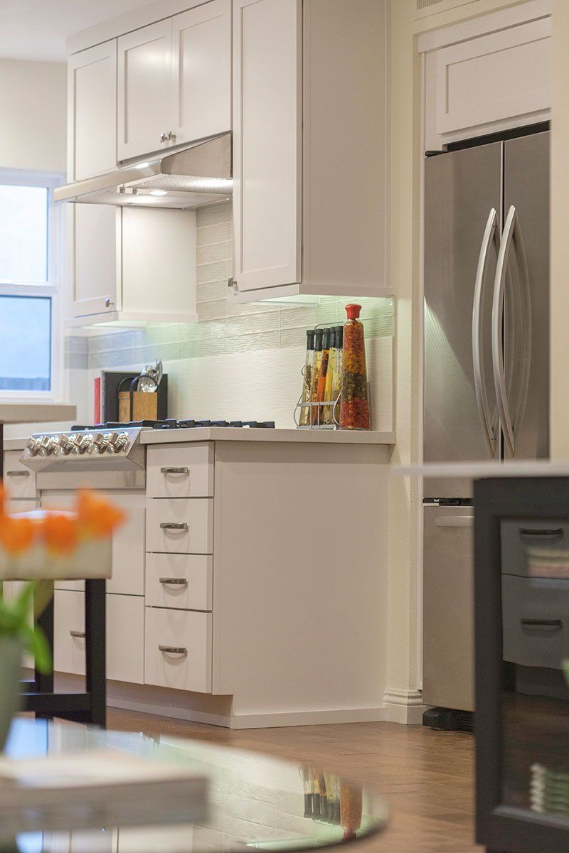Bright modern kitchen with white cabinets, stainless steel fridge, and countertop decor