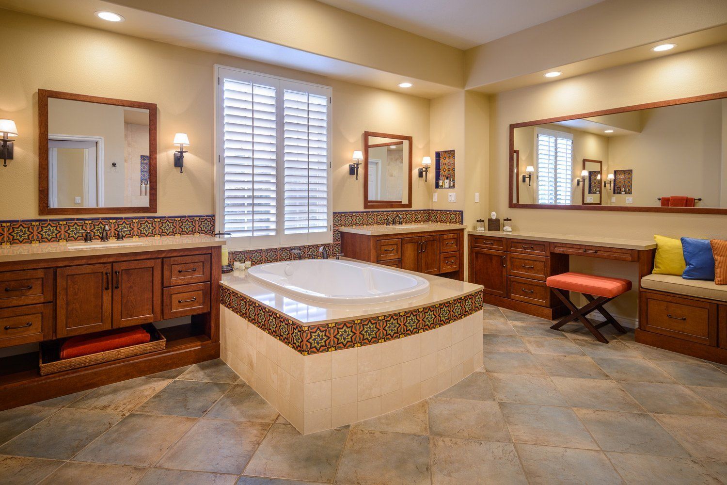 Luxurious bathroom with a sunken tub, tiled counters, mirrors, and window shutters