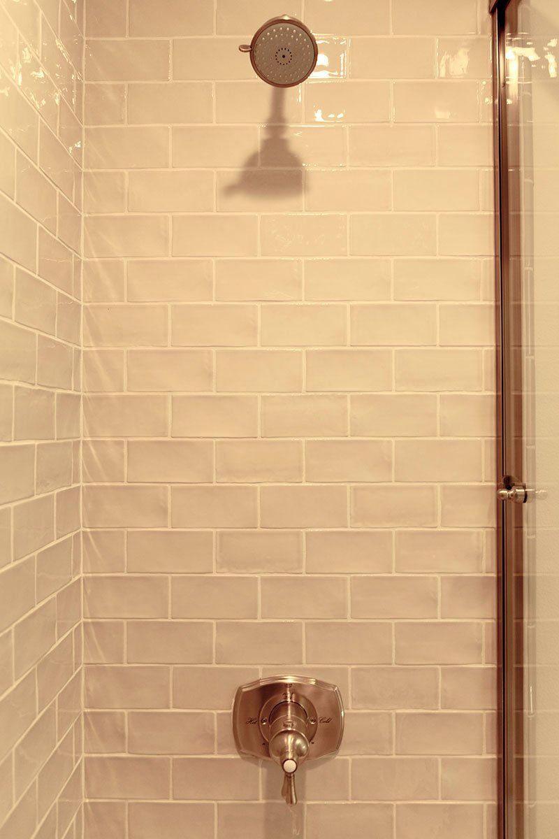 Tiled shower wall with a showerhead and faucet in a beige bathroom