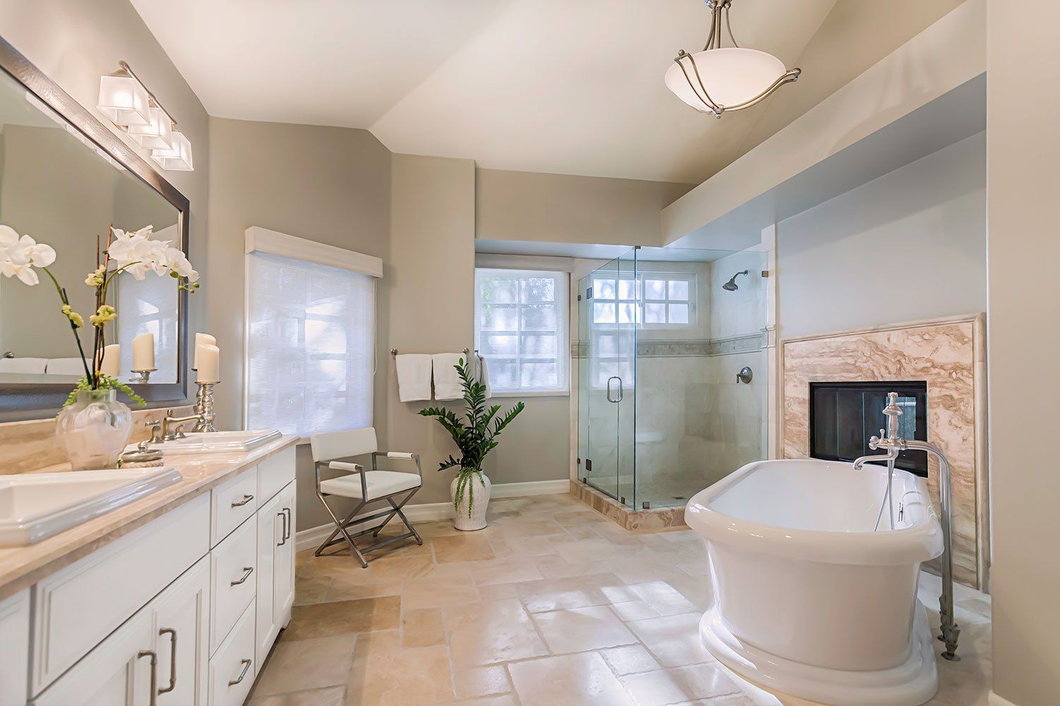 Bright spa-style bathroom with freestanding tub, glass shower, vanity, and large windows
