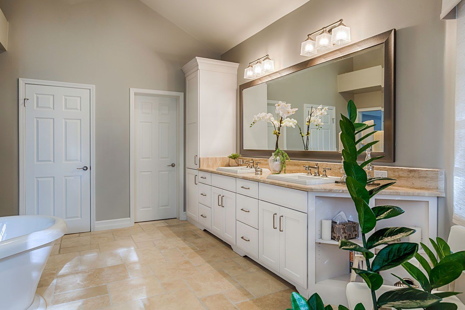 Modern bathroom with white double vanity, large mirror, and light beige tile floor