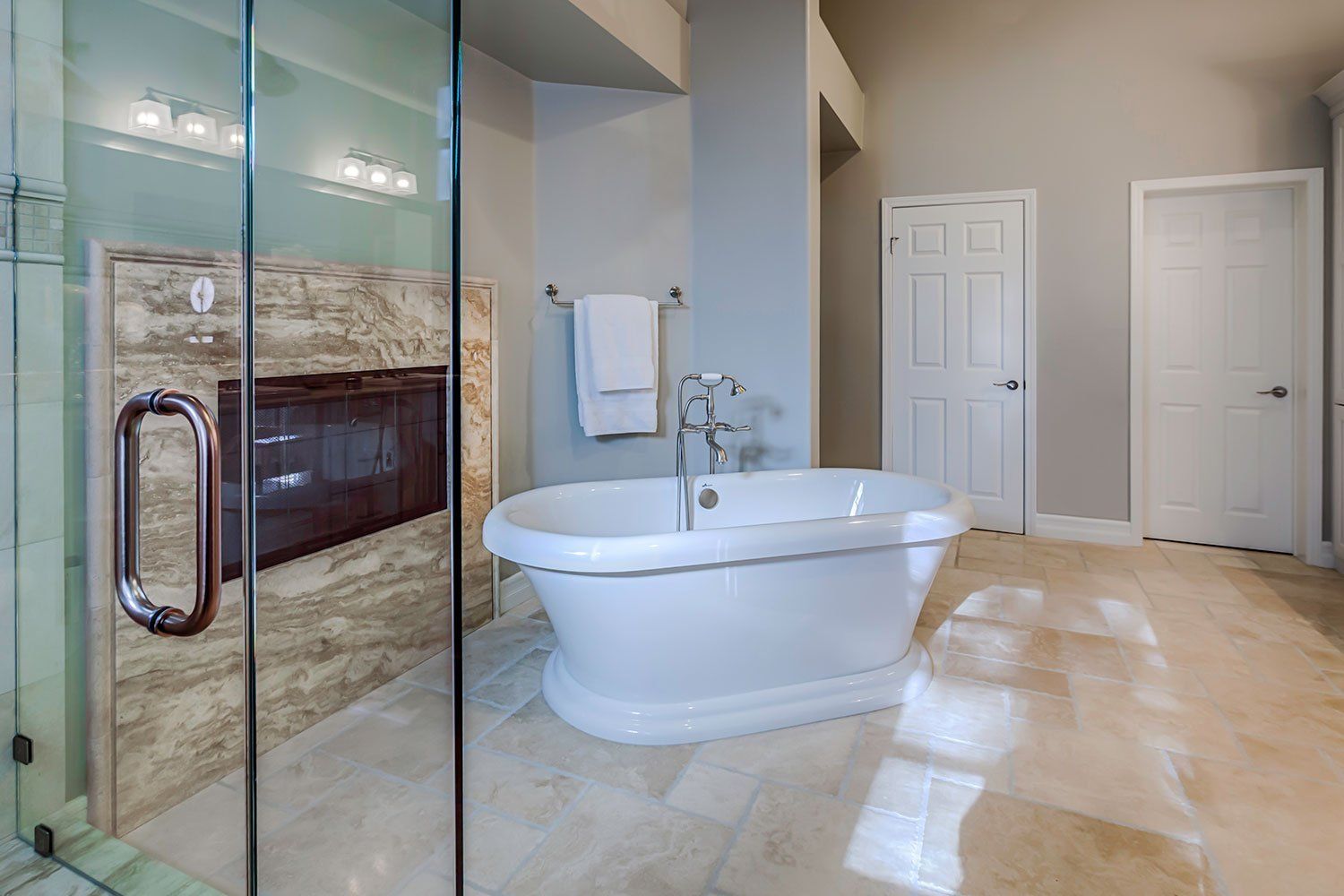 Luxurious bathroom with glass shower, freestanding tub, and beige marble tile flooring