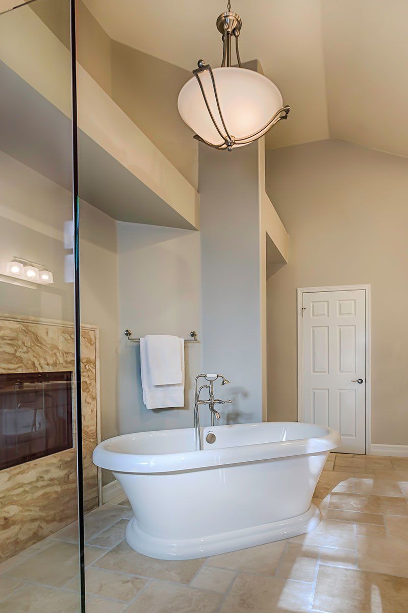 Elegant bathroom with a white clawfoot tub, beige walls, tiled floor, and hanging ceiling light.