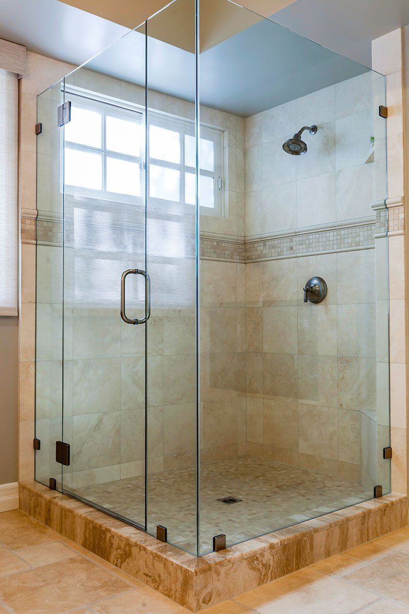 Glass corner shower with beige tile walls and a window above the showerhead