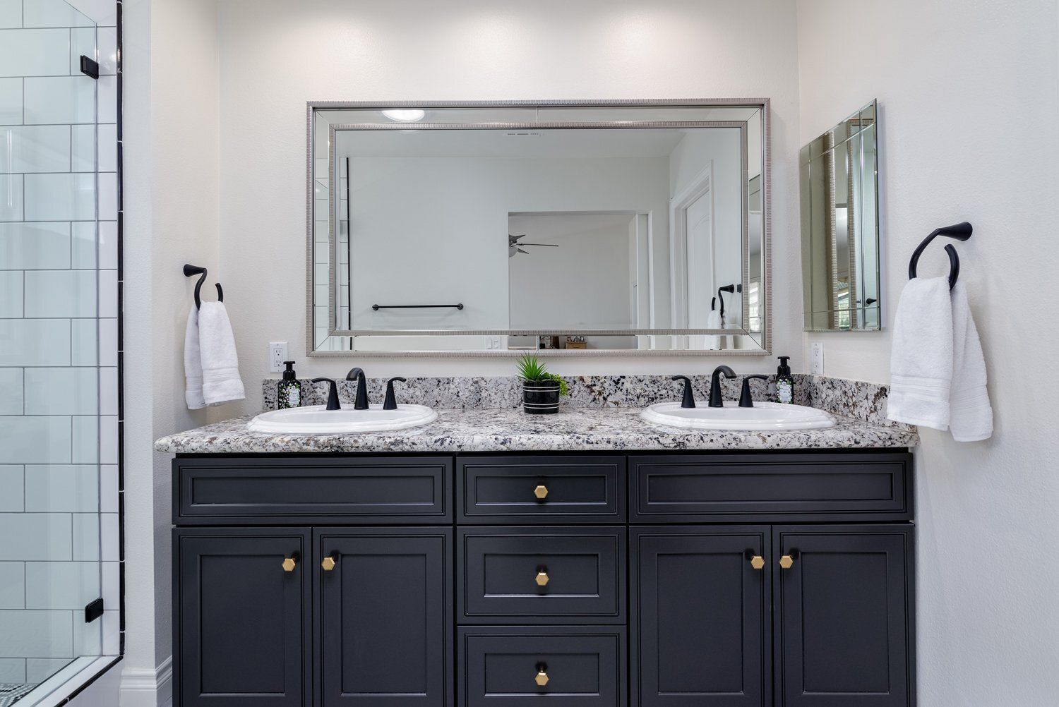 Modern bathroom vanity with double sinks, dark cabinets, large mirror, and white towels