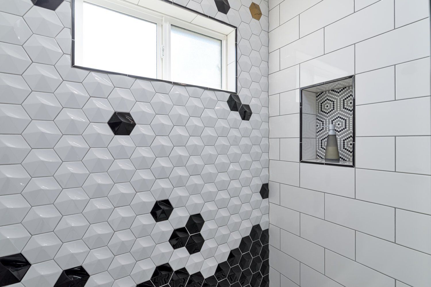 White hex tile shower with black accent tiles and a small patterned inset window on the wall